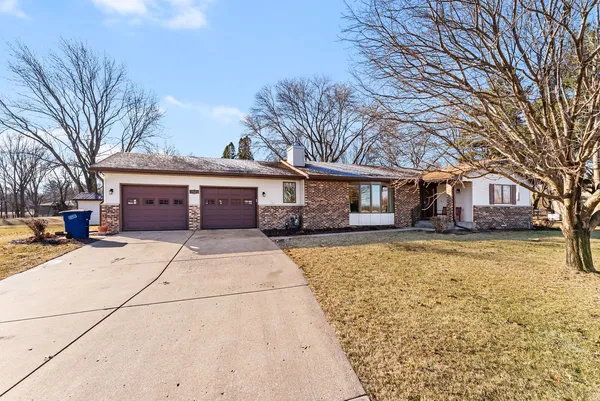 a front view of a house with a garage and large trees