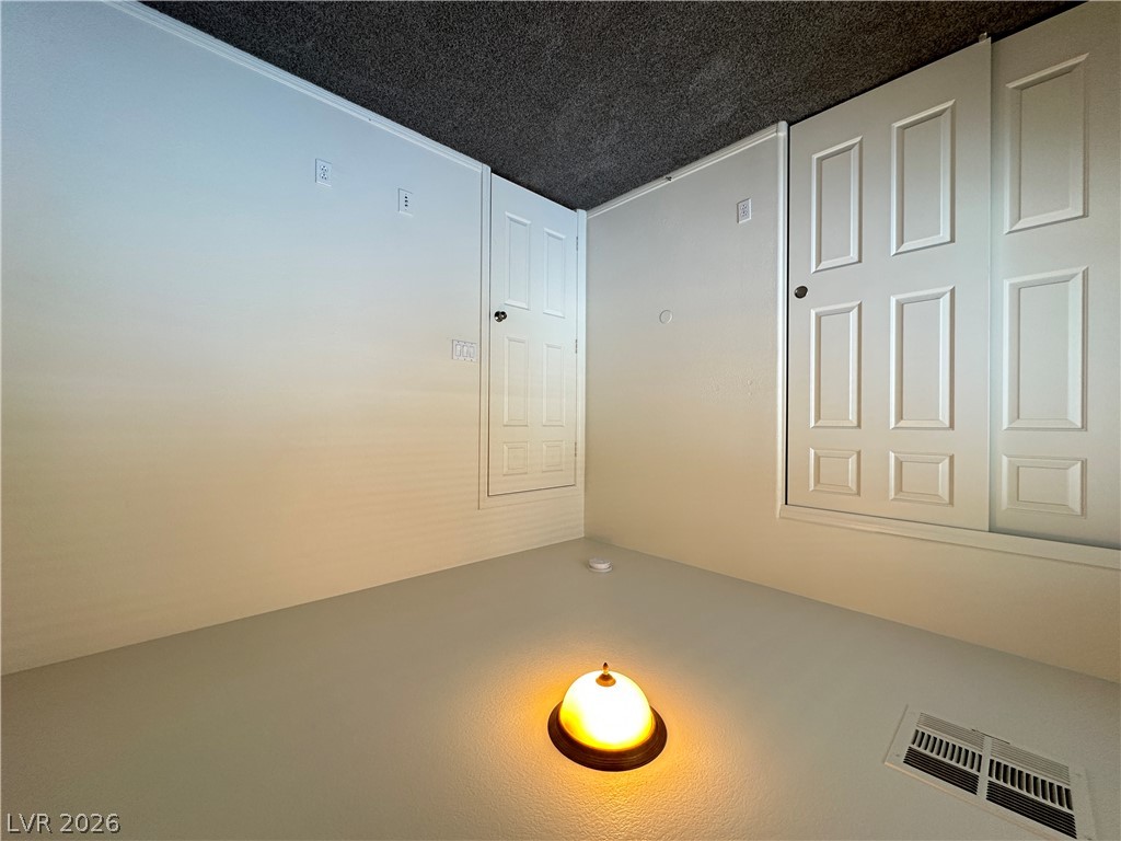 7305 Prussian Green Street Las Vegas, NV 89139 - Photo 8 of 23 An inviting room features white walls, a dark ceiling, and a bright floor lamp, with access to multiple closed doors.