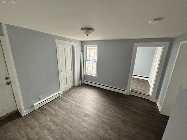 an empty room with wooden floor and window