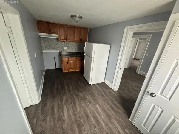 a kitchen with a refrigerator and wooden floor