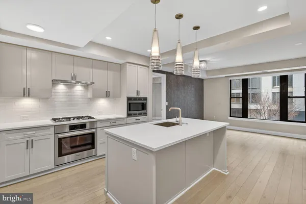a kitchen that has a sink a stove top oven and cabinetry