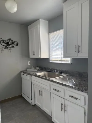 a kitchen with stainless steel appliances granite countertop white cabinets sink and dishwasher