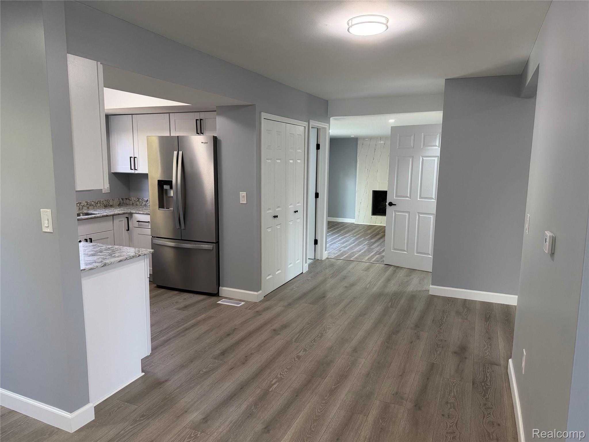 20698 Coachwood Road Riverview, MI 48193 - Photo 7 of 37 Kitchen featuring stainless steel fridge with ice dispenser, white cabinets, light stone counters, and light wood-type flooring