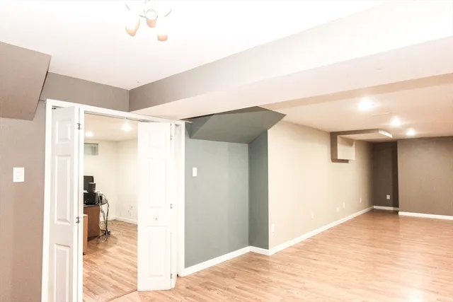 a view of a hallway with wooden floor and a bathroom