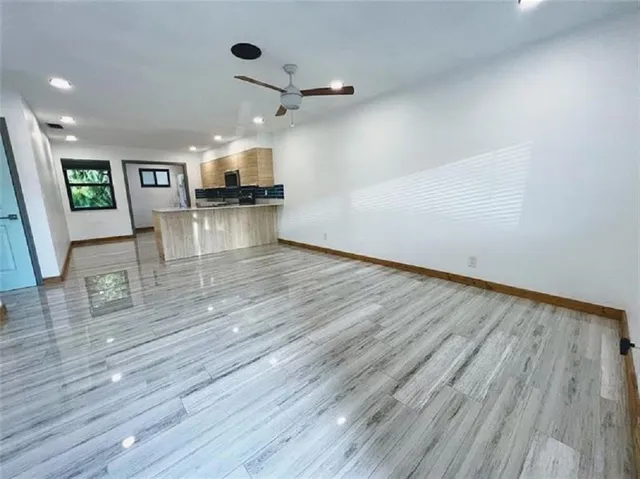 an empty room with wooden floor and a ceiling fan