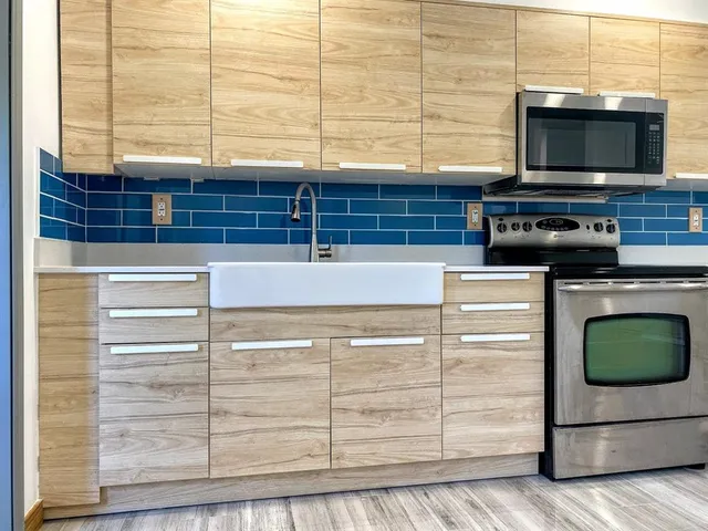 a kitchen with stainless steel appliances wooden floor and a microwave