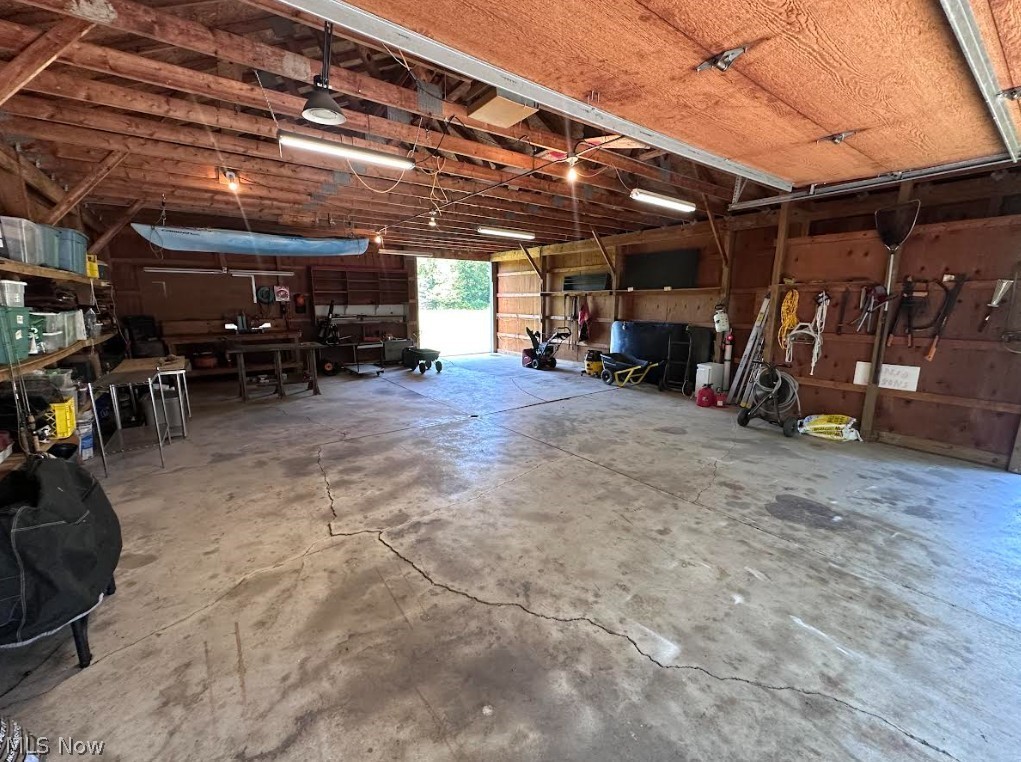 11292 Butternut Road Chardon, OH 44024 - Photo 47 of 49 Spacious garage featuring exposed wood beam ceiling, concrete flooring, fluorescent lighting, built-in shelving, and a workshop area
