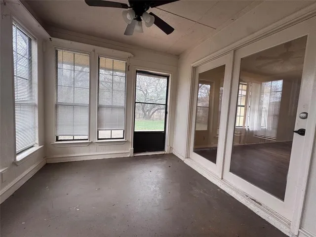 a view of an empty room with glass door and windows