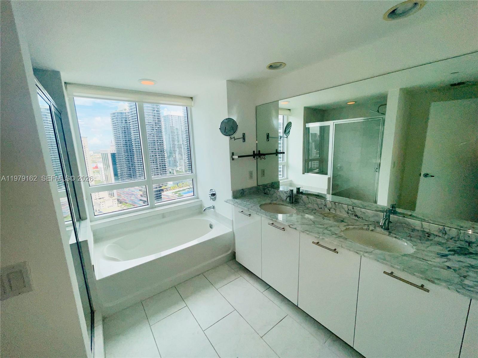 951 Brickell Avenue, Unit 3211 Miami, FL 33131 - Photo 12 of 35 a bathroom with a granite countertop sink a mirror and a bathtub