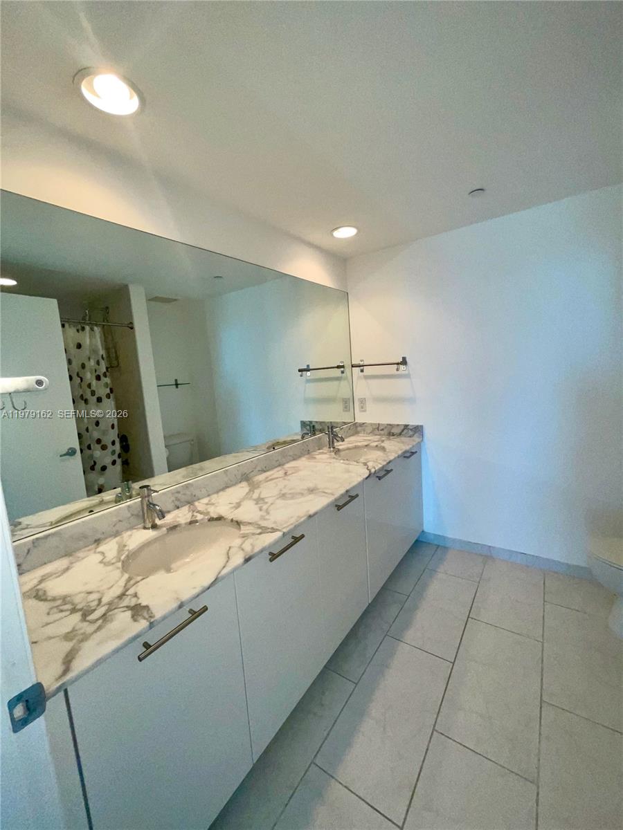 951 Brickell Avenue, Unit 3211 Miami, FL 33131 - Photo 14 of 35 a bathroom with a granite countertop sink a toilet and a mirror