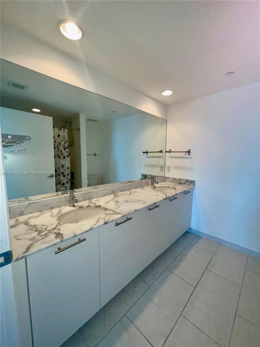 951 Brickell Avenue, Unit 3211 Miami, FL 33131 - Photo 15 of 35 a bathroom with a granite countertop sink a mirror and vanity