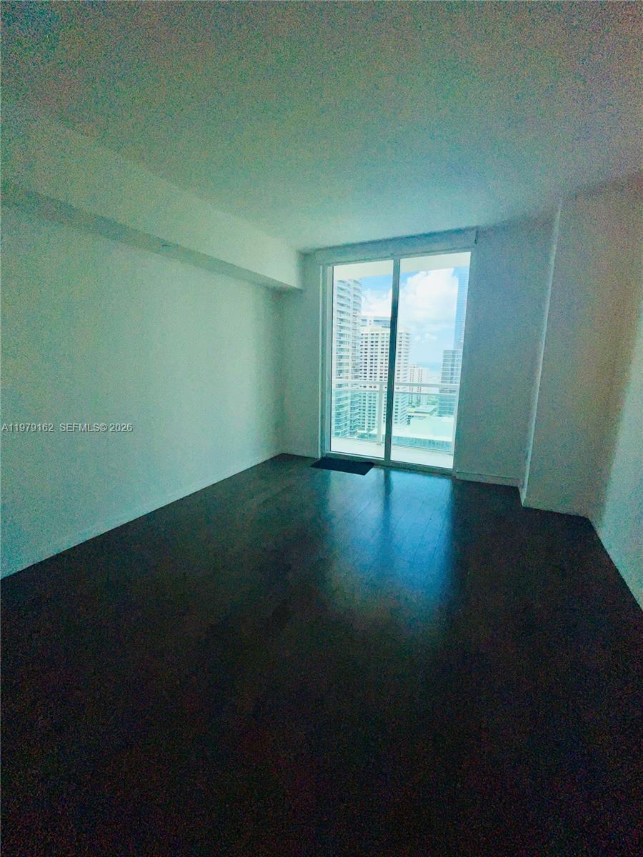 951 Brickell Avenue, Unit 3211 Miami, FL 33131 - Photo 22 of 35 a view of an empty room with wooden floor and a window