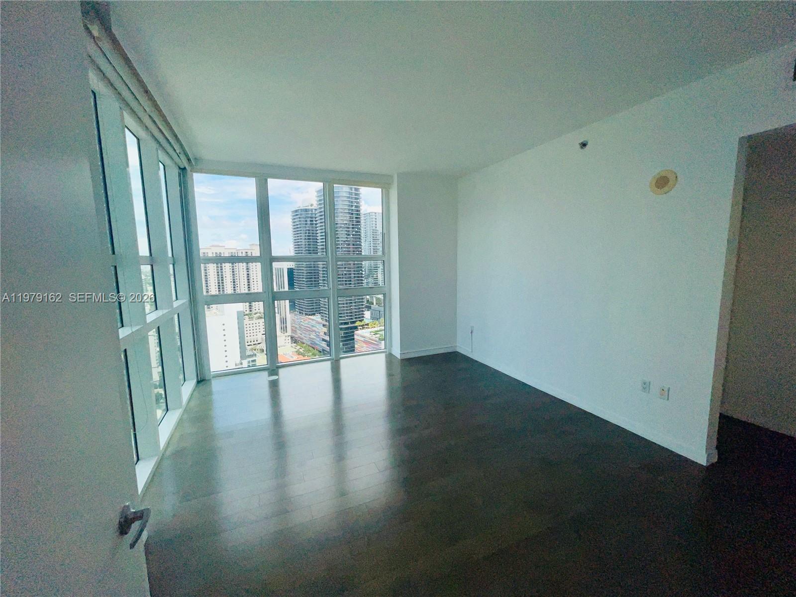 951 Brickell Avenue, Unit 3211 Miami, FL 33131 - Photo 6 of 35 a view of an empty room with wooden floor and a window