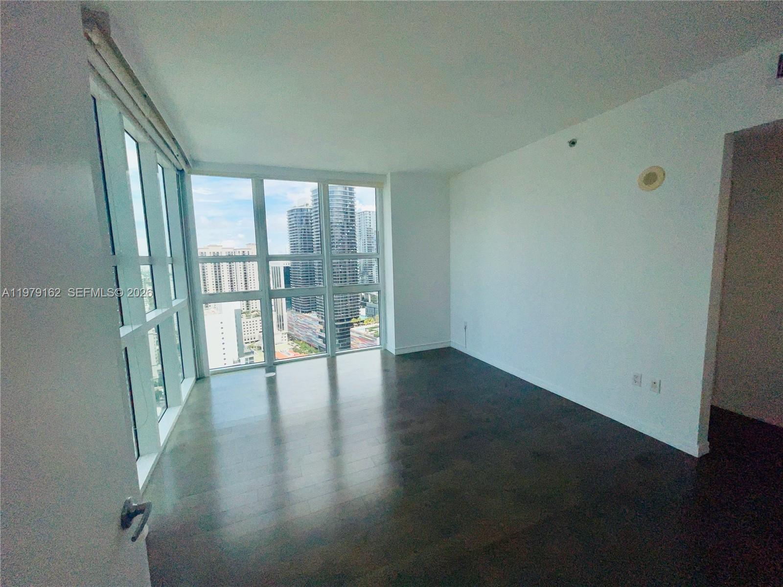 951 Brickell Avenue, Unit 3211 Miami, FL 33131 - Photo 7 of 35 a view of an empty room with wooden floor and a window