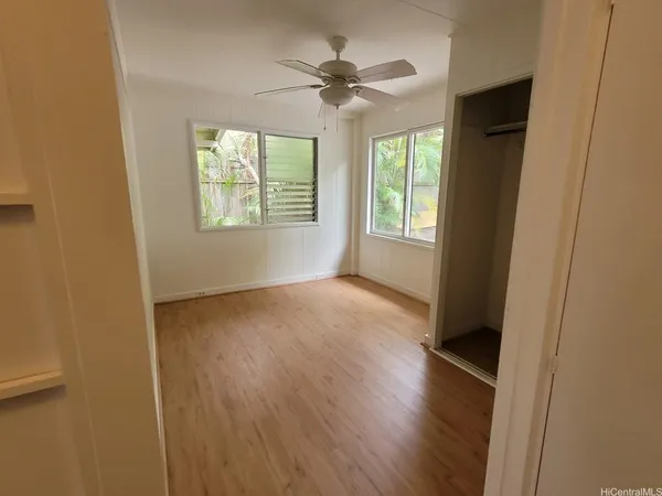 an empty room with wooden floor and windows