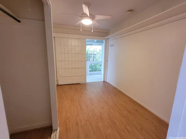 an empty room with wooden floor cabinet and windows