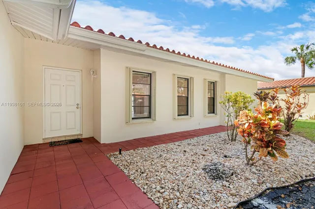 a view of a yard with flower plants and large trees