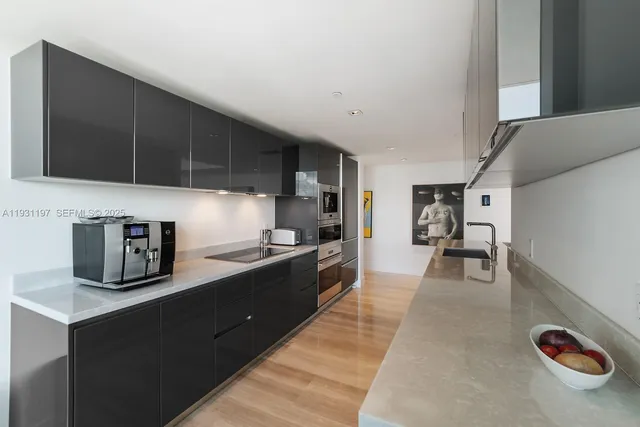 a kitchen with granite countertop a stove a sink a refrigerator and blue cabinets