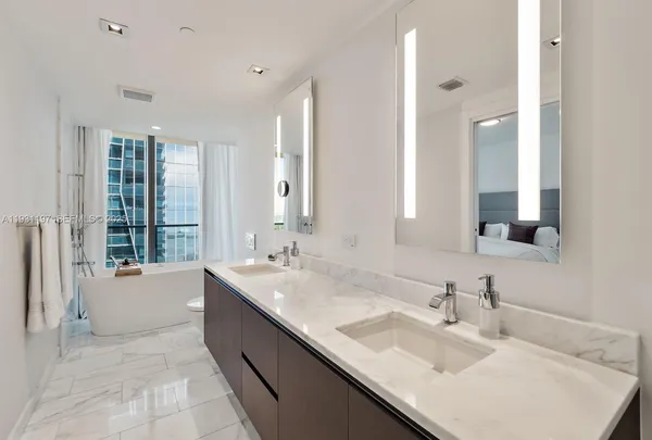 a large bathroom with a granite countertop double vanity sink a mirror and a bathtub