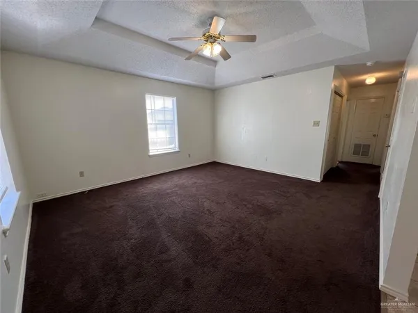 an empty room with chandelier fan and windows