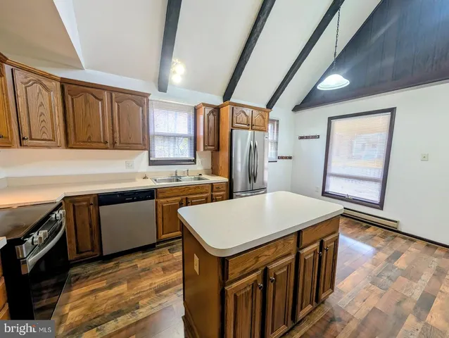 a kitchen with a stove a sink dishwasher and a refrigerator with wooden floor
