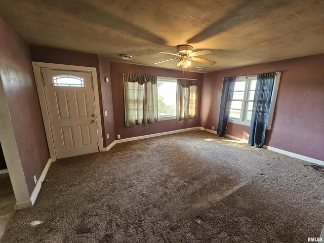 an empty room with windows and fan