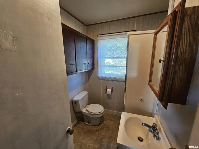 a view of an empty room with wooden floor and a ceiling fan