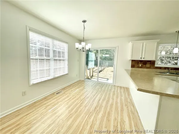 a view of a kitchen with kitchen island a large window wooden floor and stainless steel appliances