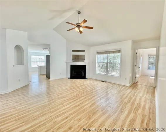 a view of empty room with wooden floor and fan