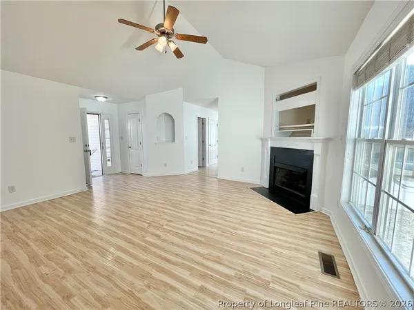 a view of empty room with wooden floor and fan