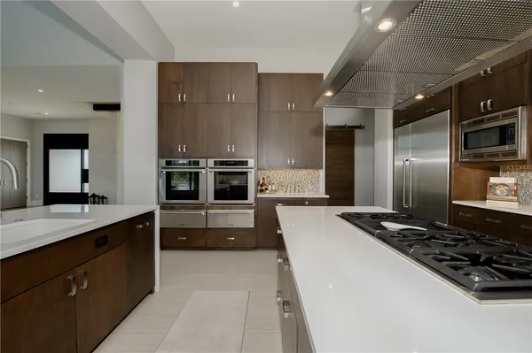a large kitchen with stainless steel appliances a stove a sink and a refrigerator