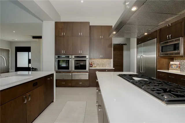a large kitchen with stainless steel appliances a stove a sink and a refrigerator