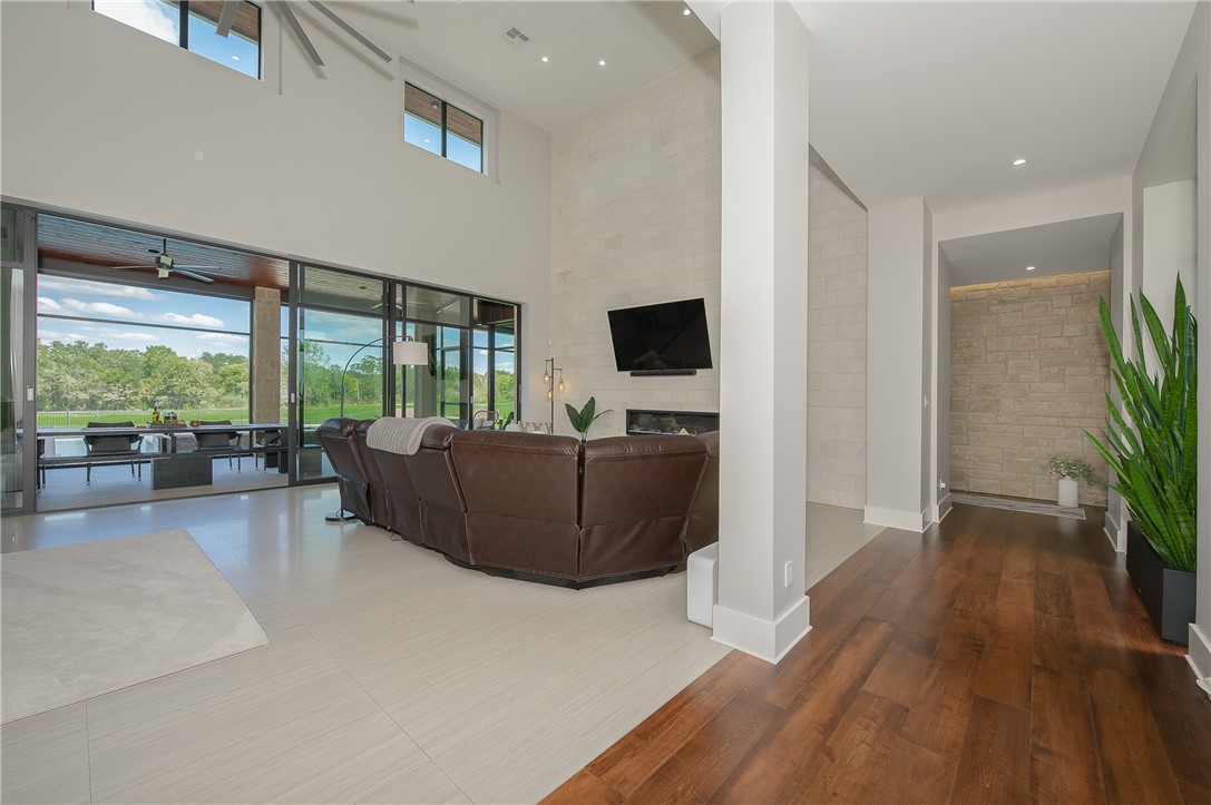 3320 Sycamore Trail Bryan, TX 77807 - Photo 5 of 49 Living room with a fireplace, a high ceiling, wood finished floors, visible vents, and ceiling fan
