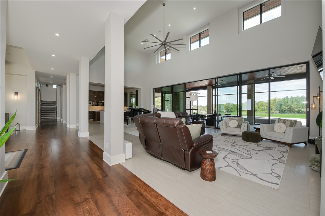 3320 Sycamore Trail Bryan, TX 77807 - Photo 8 of 49 Living room with stairway, a ceiling fan, a high ceiling, wood finished floors, and baseboards