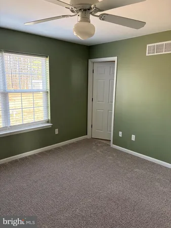 an empty room with a ceiling fan and a window