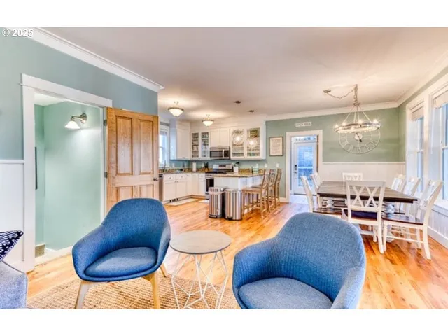 a living room with stainless steel appliances kitchen island granite countertop a table chairs and a living room view
