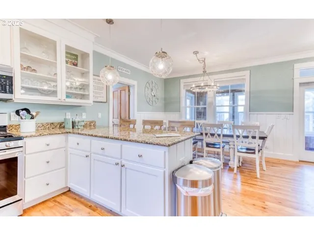 a kitchen with granite countertop a stove a sink a dining table and chairs