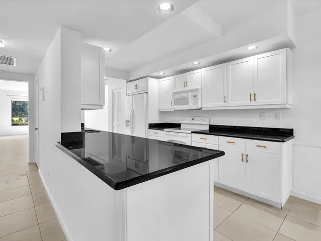 a kitchen with stainless steel appliances granite countertop a sink a stove and white cabinets