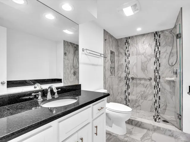 a bathroom with a granite countertop sink toilet a shower and a mirror