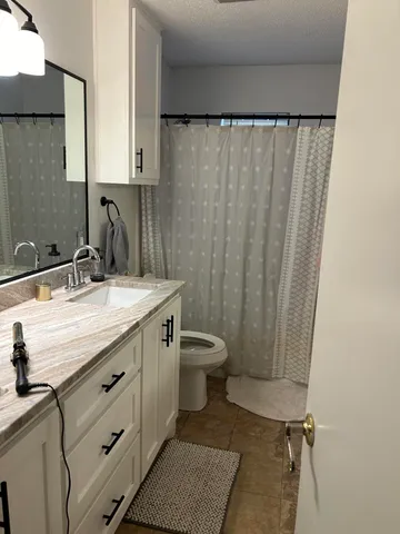 a bathroom with a granite countertop sink a toilet and a mirror