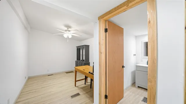 a view of a hallway with wooden floor and a bathroom
