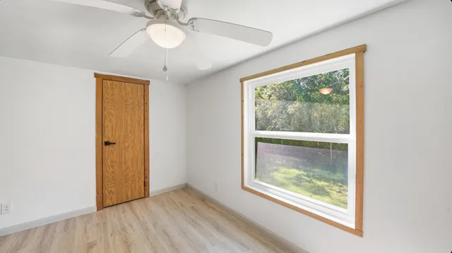 a view of an empty room with a window and wooden floor