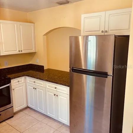 a kitchen with white cabinets and refrigerator