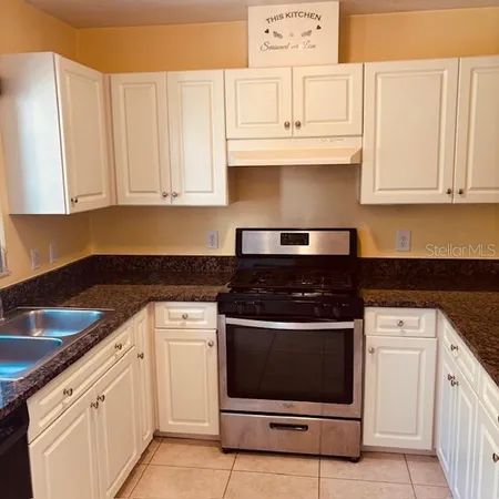 a kitchen with granite countertop white cabinets and white appliances