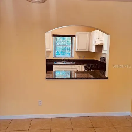 a kitchen with granite countertop white cabinets and window