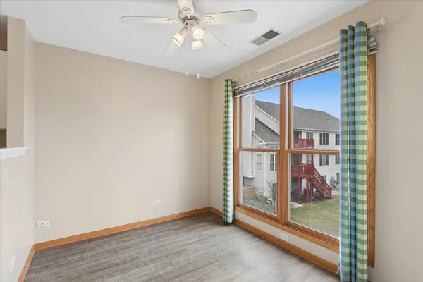 an empty room with wooden floor fan and windows