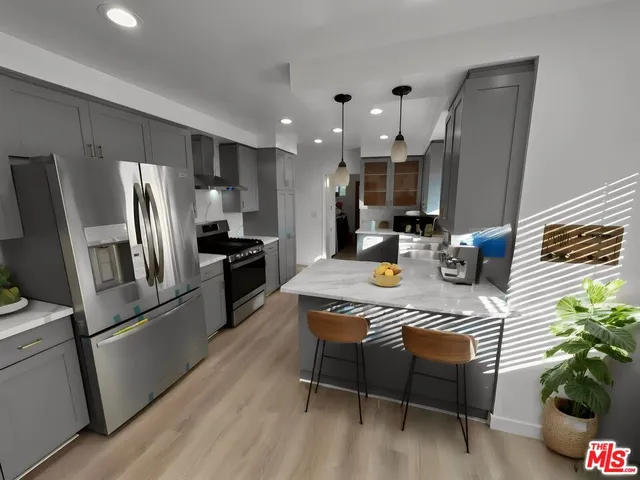 a kitchen with stainless steel appliances granite countertop a refrigerator a sink dishwasher a stove a dining table and chairs with wooden floor