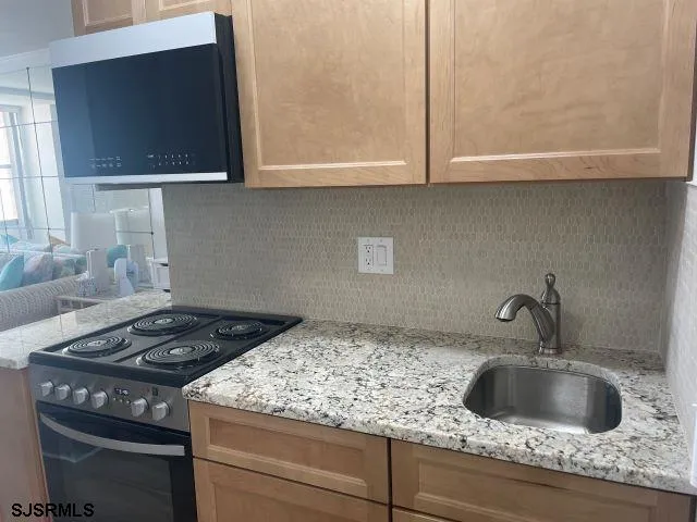 a kitchen with granite countertop a sink stove and cabinets