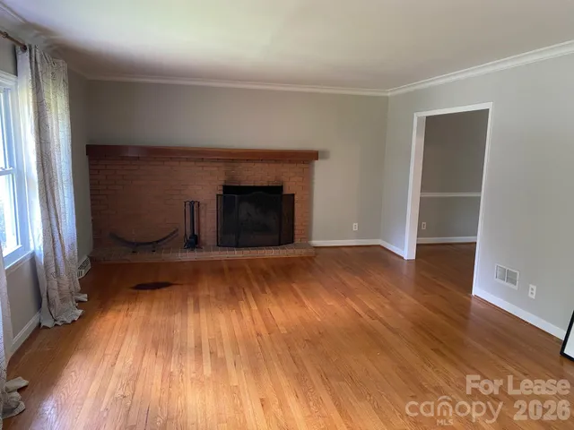 an empty room with wooden floor a fireplace and windows