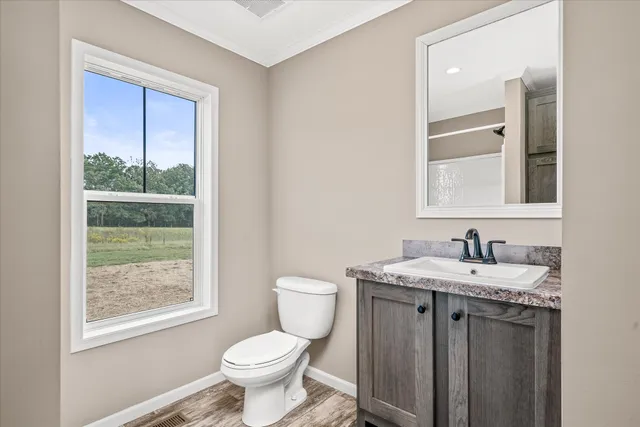 a bathroom with a granite countertop toilet a sink and a window